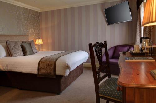 a hotel room with a bed and a desk and a chair at Knights Hill Hotel & Spa in Kings Lynn
