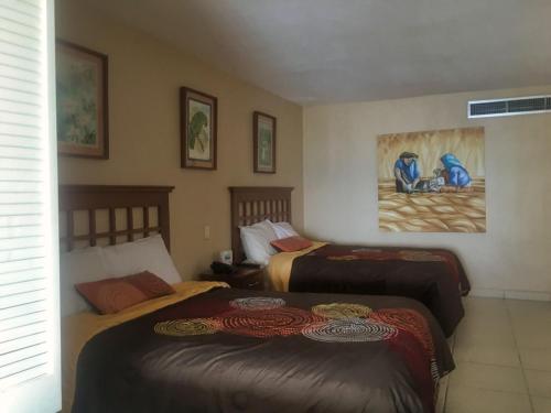 a bedroom with two beds and a painting on the wall at Torre Condomar Beside Sunscape in Puerto Vallarta