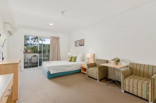 a hotel room with a bed and two chairs at Quality Suites Pioneer Sands in Wollongong