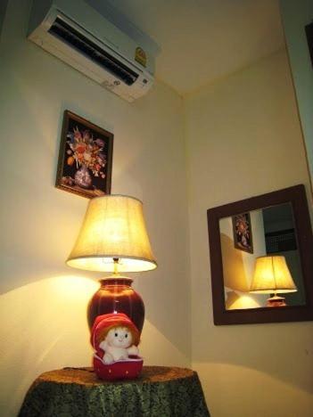 Una lámpara en una mesa con una muñeca. en Choktawee Mansion Lampang, en Lampang