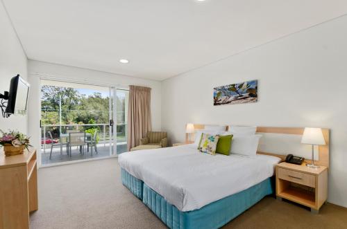 a bedroom with a large bed and a large window at Quality Suites Pioneer Sands in Wollongong