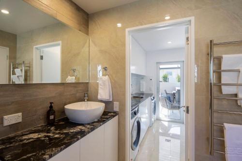 uma casa de banho com um lavatório e uma máquina de lavar roupa em Mountain Vista - recently renovated beautiful home with spa pool em Queenstown