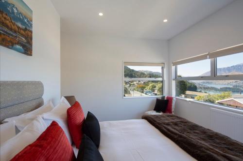 a bedroom with a bed with red and white pillows at Mountain Vista - beautifully renovated home with spa pool in Queenstown