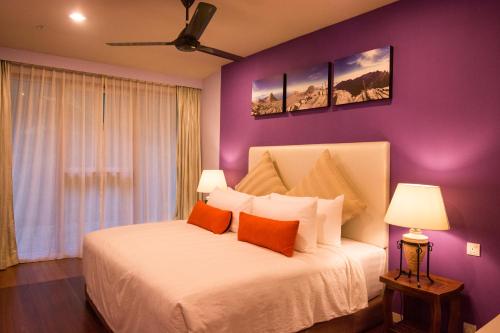 a bedroom with a white bed with purple walls at Sutera Sanctuary Lodges At Kinabalu Park in Kundasang