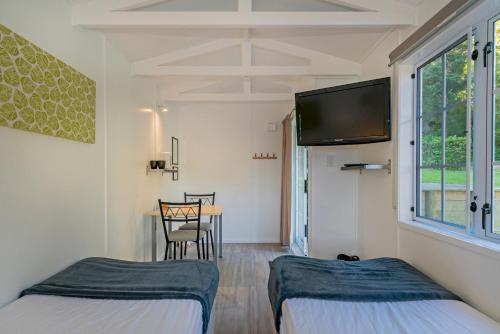 a room with two beds and a table with a tv at Anglers Lodge in Coromandel Town