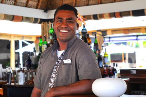 a man standing behind a bar with a smile at Paradise Cove Resort in Naukacuvu Island