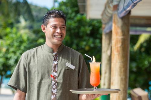 a man holding a tray with a drink on it at Paradise Cove Resort in Naukacuvu Island