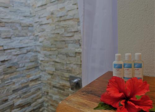 a red flower on a wooden table with three bottles at Paradise Cove Resort in Naukacuvu Island