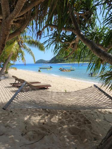 a hammock and a bench on a beach at Paradise Cove Resort in Naukacuvu Island