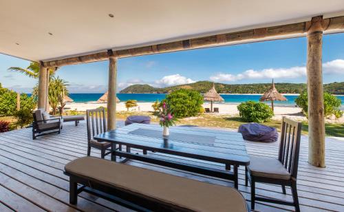 a wooden deck with a table and chairs on the beach at Paradise Cove Resort in Naukacuvu Island