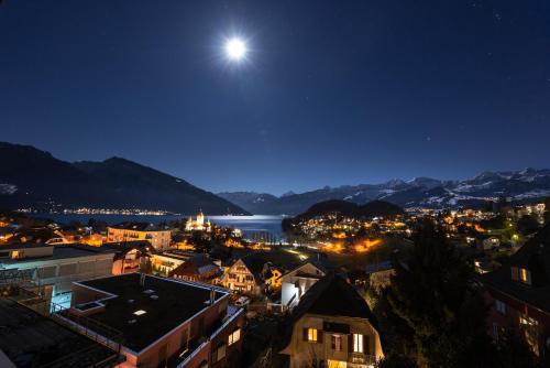 a view of a city at night with the moon at la belle vue Boutique Hotel & Café in Spiez