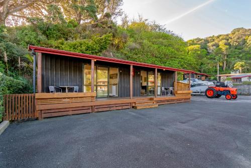 a cabin with a red tractor parked in a parking lot at Anglers Lodge in Coromandel Town
