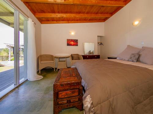 a bedroom with a large bed and a table with a table at Hahei Hideaway - Hahei Holiday Home in Hahei