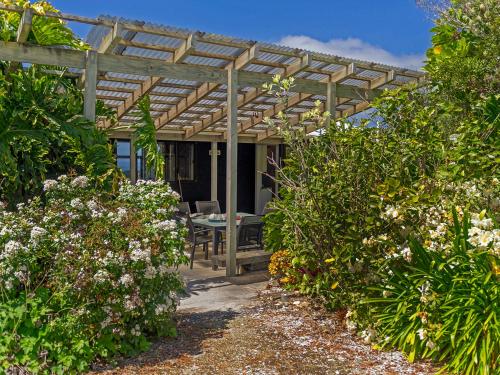 a wooden pergola with a table in a garden at Hahei Hideaway - Hahei Holiday Home in Hahei