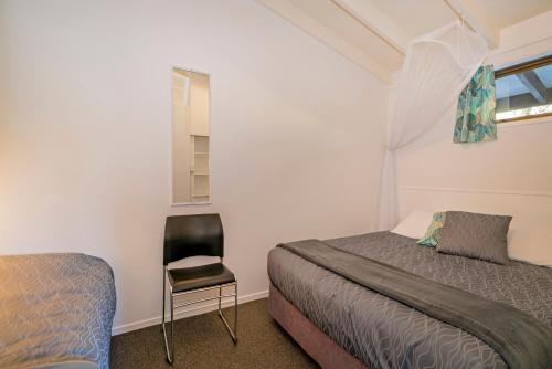 a bedroom with a bed and a chair in it at Anglers Lodge in Coromandel Town
