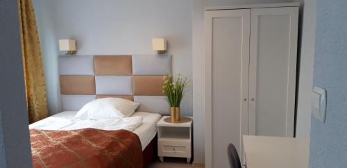 a bedroom with a bed and a vase of flowers at Noclegi Gwardia in Koszalin