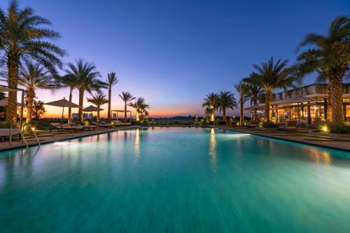 a large swimming pool with palm trees and a building at Mia Saigon – Luxury Boutique Hotel in Ho Chi Minh City