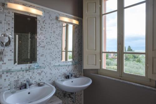 a bathroom with two sinks and two windows at Fontelunga Hotel & Villas in Pozzo