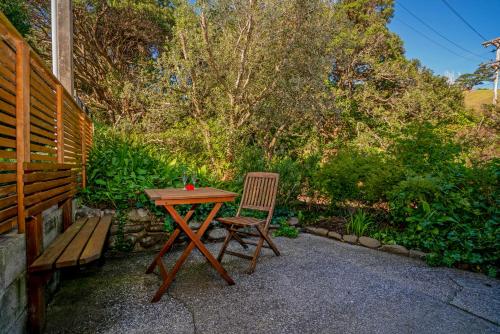 a wooden table and a chair next to a bench at Anglers Lodge in Coromandel Town