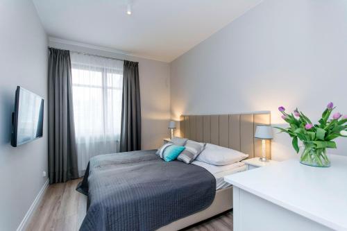 een slaapkamer met een bed en een vaas met bloemen bij Vanilla Rentyear Apartments in Gdańsk