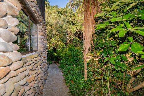 a stone wall next to a path next to a building at Anglers Lodge in Coromandel Town