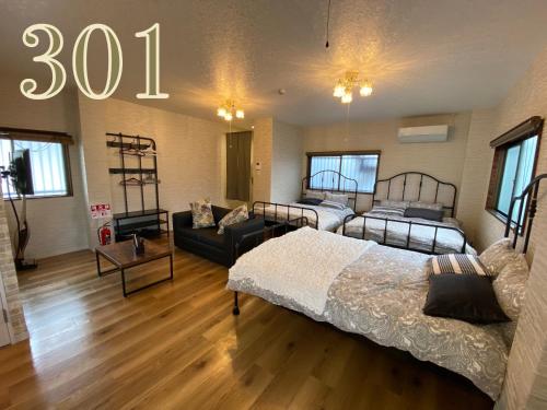 a room with two beds and a couch in it at GUEST HOUSE APPLE in Osaka