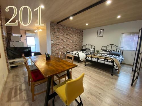 a room with four beds and a table and chairs at GUEST HOUSE APPLE in Osaka
