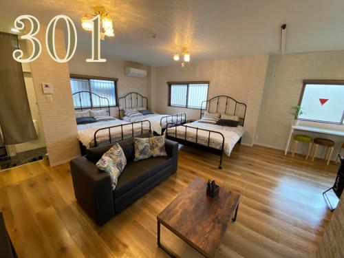 a living room with two beds and a couch at GUEST HOUSE APPLE in Osaka