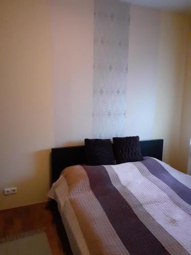 a bedroom with a bed with a blanket and a window at Mónika Apartman (Tapolca) in Tapolca