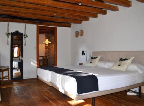 een groot wit bed in een kamer met houten plafonds bij La Casita Del Rincón Del Vino in Ezcaray