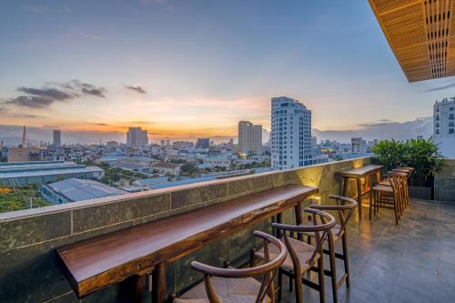 a row of bar stools on a rooftop overlooking a city at Platinum Danang Hotel in Da Nang