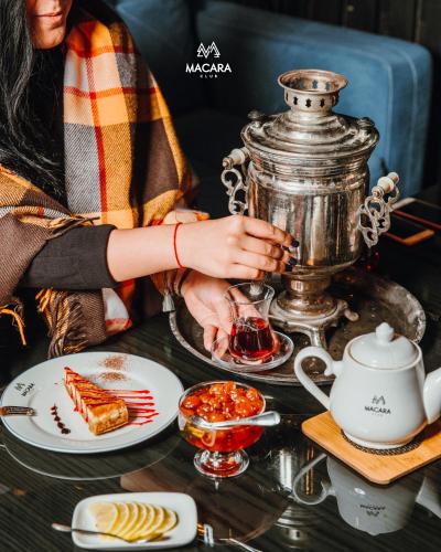 una donna seduta a un tavolo con del cibo e un frullatore di Macara Village Resort a Quba
