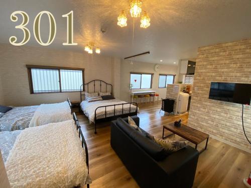 a large room with two beds and a tv at GUEST HOUSE APPLE in Osaka