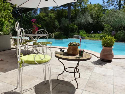 un tavolo e sedie con ombrellone accanto a una piscina di la pause nimoise a Nîmes