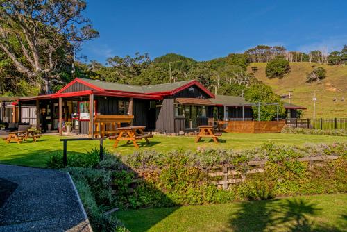 a building with picnic tables in front of it at Anglers Lodge in Coromandel Town