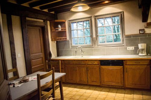 a kitchen with wooden cabinets and a sink and a table at chaumière de l'épine in La Crique