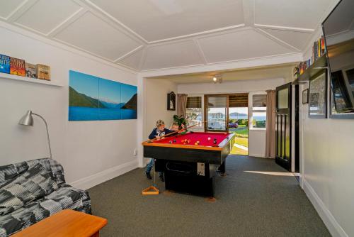 a boy in a room with a pool table at Anglers Lodge in Coromandel Town