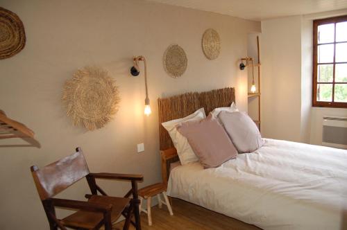 um quarto com uma cama, uma cadeira e uma janela em LOU CLEDOU em Cendrieux