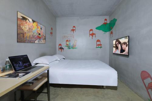 a bedroom with a bed and a desk with a laptop at Colour Inn - She Kou Branch in Shenzhen