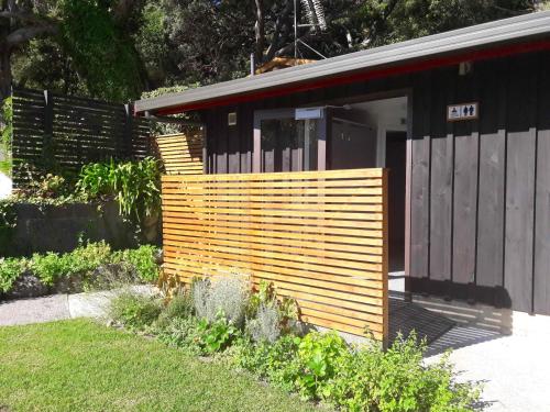 a house with a wooden fence next to a yard at Anglers Lodge in Coromandel Town