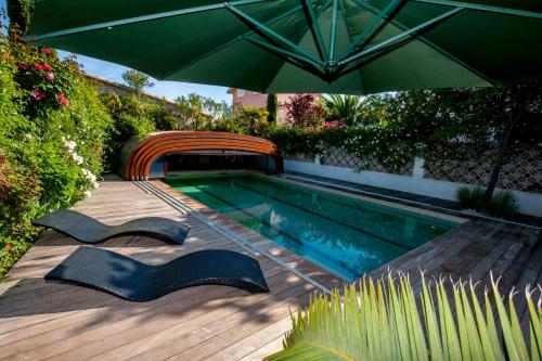 - une piscine avec un parasol vert et une piscine dans l'établissement La Villa ioanes, à Port-Saint-Louis-du-Rhône
