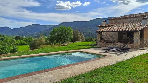 una piscina frente a una casa con montañas en Can Nofre - Masia familiar en zona tranquila, en Amer