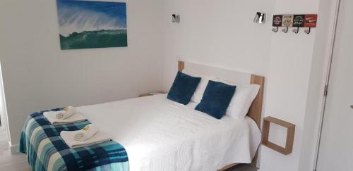 a bedroom with a white bed with blue pillows at Casa do Miguel in Foz do Arelho