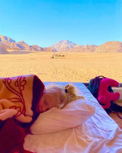 a little girl sleeping on a bed in the desert at Wadi Rum Dream Camp in Wadi Rum