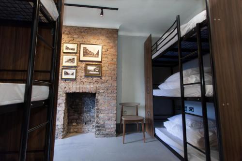 ロンドンにあるパブラブ @ ザ クラウン バタシーの二段ベッド2台と暖炉が備わる客室です。
