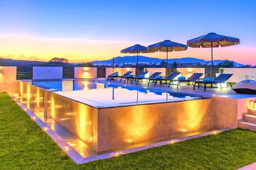 - une piscine avec des chaises et des parasols au-dessus d'une maison dans l'établissement Villa Solaris Heated Pool & Jacuzzi, à Georgioúpoli