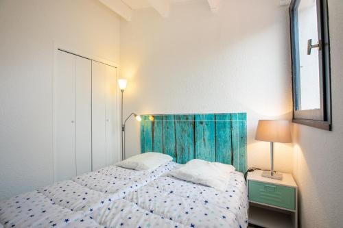 1 dormitorio con 1 cama con cabecero azul en Calypso, en Cap d'Agde