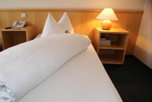 a hotel room with a large white bed with a lamp at Hotel Herian in Parsdorf