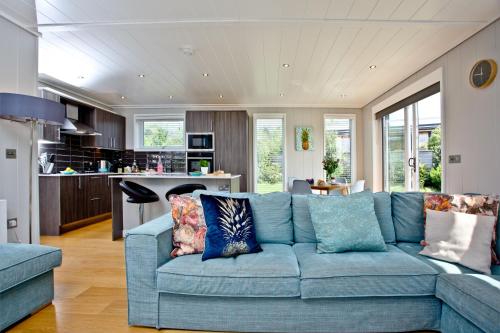 a living room with a blue couch and a kitchen at Pamela's Meadow, Strawberryfield Park in Cheddar