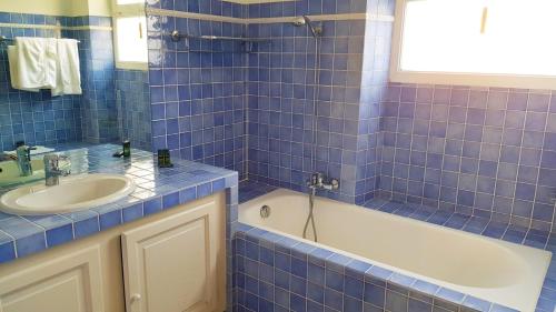 a blue tiled bathroom with a tub and a sink at Hôtel Les Palmiers in Saint-Tropez